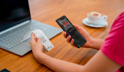 Woman using contactless payment by mobile phone with QR code at cafe