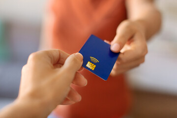 Closeup shot of young woman giving blue credit card to female hand