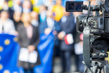 Filming political meeting or publicity event with television camera, European Union flag in...