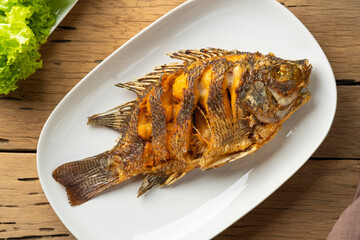 Deep fried Tilapia fish in white plate.Top view