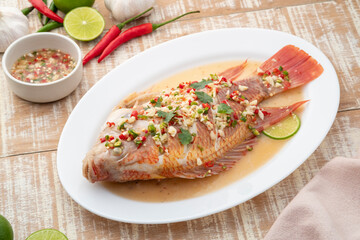 Steamed Red Tilapia Fish In Spicy Lime Soup on white plate