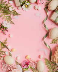 beautiful easter frame composition with wooden easter eggs, flowers, ribbons and gifts on a pastel pink background. top view. copy space. flat lay. place for text.