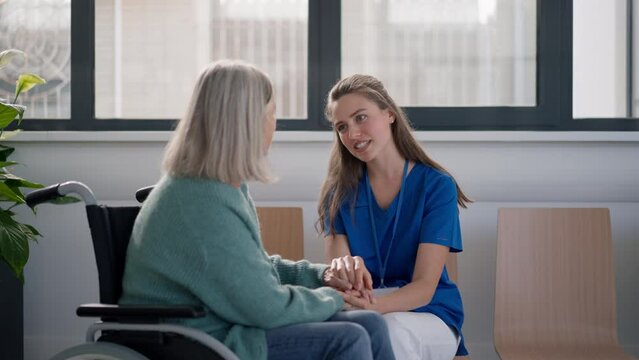 Young woman doctor talking with senior woman at wheelchair.