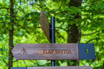 Hiking sign towards Savica Waterfall in the forest of Bohinj Lake area, Triglav National Park, Julian Alps, Slovenia. Text: 