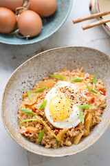 Bowl of kimchi fried rice topped with chicken egg, vertical shot, middle closeup