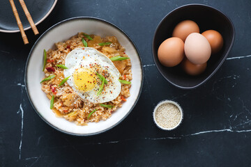 Bowl of korean kimchi fried rice on a black marble background, horizontal shot, top view