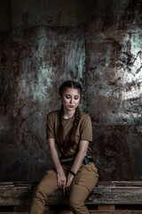 American pilot. A beautiful young woman in a uniform and with a weapon on the background of a metal wall. Staged photo. Studio light.