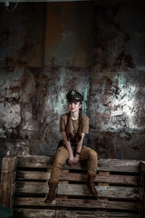 American pilot. A beautiful young woman in a uniform and with a weapon on the background of a metal wall. Staged photo. Studio light.