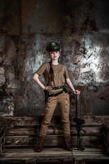 American pilot. A beautiful young woman in a uniform and with a weapon on the background of a metal wall. Staged photo. Studio light.