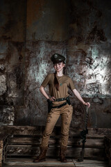 Fototapeta na wymiar American pilot. A beautiful young woman in a uniform and with a weapon on the background of a metal wall. Staged photo. Studio light.