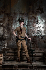 American pilot. A beautiful young woman in a uniform and with a weapon on the background of a metal wall. Staged photo. Studio light.