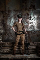 Fototapeta na wymiar American pilot. A beautiful young woman in a uniform and with a weapon on the background of a metal wall. Staged photo. Studio light.