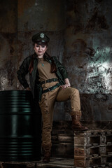 American pilot. A beautiful young woman in a uniform and with a weapon on the background of a metal wall. Staged photo. Studio light.