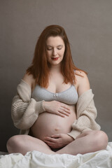 Smiling mother-to-be looking at her baby bump - Studio portrait of a young pregnant woman.