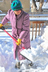 Mature female shoveling snow outside.