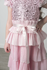 details of an embroidered pink dress with sequins and pleated belt zone. Girgl wearing shyny party...
