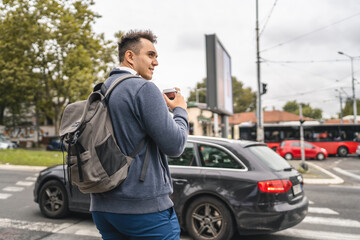 one young adult man student or tourist hold cup of coffee at crosswalk