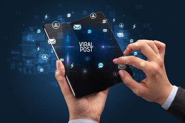Businessman holding a foldable smartphone, social media concept