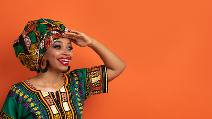 Cheerful black woman in african costume looking at copy space