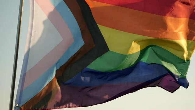 Concept of LGBT History Month, Pride Month, LGBT Lesbian, Gay, Bisexual, Transgender, Queer or Questioning, Parade. Six-band Rainbow flag waving in wind,  outdoor background, soft focus. Slow motion
