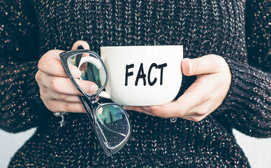 FACT, text on a cup of coffee in woman hand