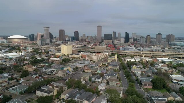 Aerial Forward Shot Of Caesars Superdome Amidst Tall Buildings By Cars Moving On Roads In City - New Orleans, Louisiana
