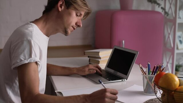Young man freelancer student using laptop studying online working from home in internet, smiling focused millennial guy typing on computer surfing web looking at screen enjoying distant job