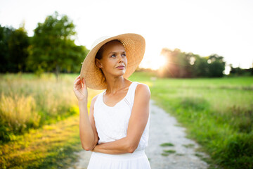 Pretty, young elegant woman with a hat in warm evening sunlight