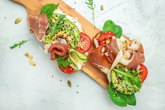 Open sandwich with prosciutto or jamon, avocado and fresh greens. Keto breakfast or snack, top view