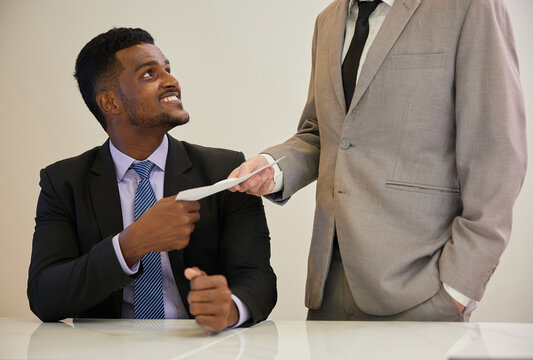 African businessman giving envelope to his boss in the office