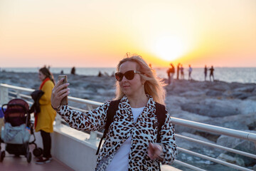 A stunning blonde traveler who is taking advantage of Dubai's hospitality is shown in the pice. Her hair is flying in the breeze, giving her a fun appearance, and she has a bright, amiable grin.