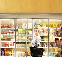 Woman choosing frozen food from a supermarket freezer, reading product information