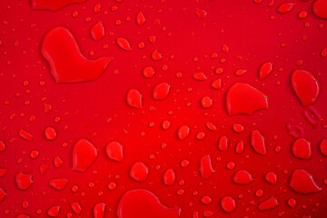 Large and small drops of water on a red background.