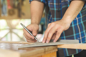 Fototapeta na wymiar Carpentry professional, hand of asian young man, male carpenter use ruler measure, tool on board wood in small shop. Woodwork, furniture making, construction industry. Owner small business people.