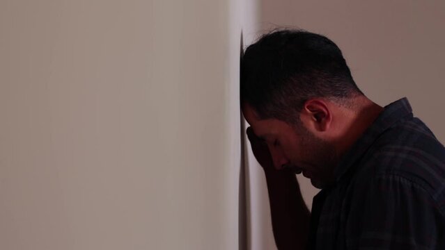 Video of person leaning his head against a wall, worried, stressed, with many problems, pensive, resigned, frustrated. Concept of lifestyles, problems, societal problems.