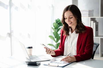 young businesswoman looking at financial information from a mobile phone, she is checking company financial documents, she is a female executive of a startup company. Concept of financial management.