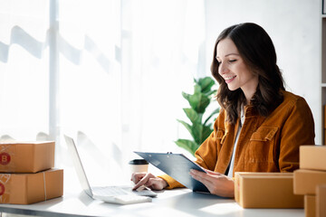 A beautiful business owner opens an online store, she is checking orders from customers, sending...