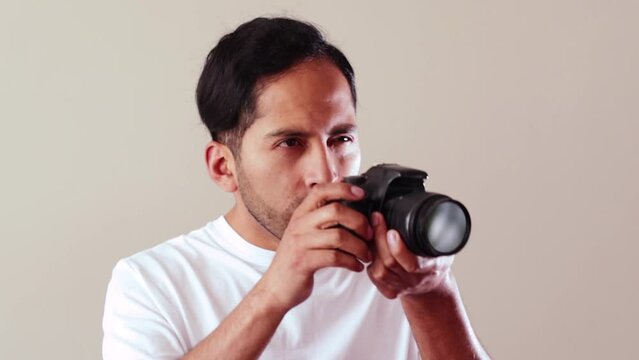 Video of male photographer indicating and taking a photo on a light background. Concept of technology, professions, lifestyles and arts.