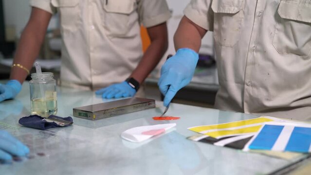 Factory worker spreading orange paint for sample test