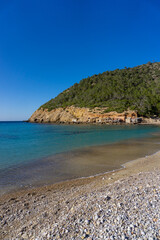 Cove on the coast of Ibiza, with the fishermen's houses, on a sunny day, and without people.