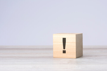 natural wooden cube with exclamation mark on grey background