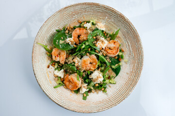 Salad with shrimp, quinoa, arugula, spinach, cucumbers, cream cheese, pine nuts and dressing.