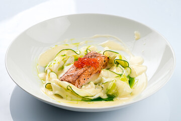 Lunch fried salmon fish with raw zucchini, red caviar and sauce.