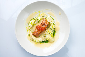 Fried salmon fish with raw zucchini, red caviar and sauce.