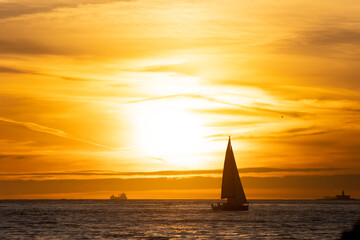 Sailboat sails the river at sunset