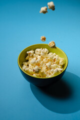 Popcorn looked down from above on a yellow background. The bowl of popcorn was lying flat. Top View.