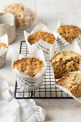 Morning breakfast oatmeal muffins in white paper cups on cooling rack on white textured background