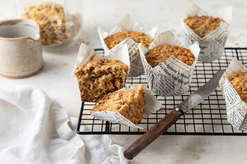 Morning breakfast oatmeal muffins in white paper cups on cooling rack on white textured background