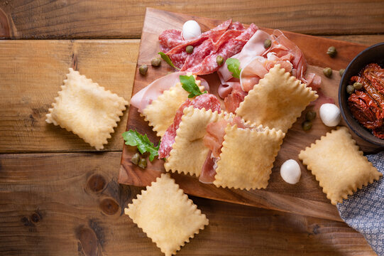 Crescentina. Food of Emilia Romagna region, deep fried bread gnocco fritto or crescentina. Starter or aperitif in Italy. Creshantina with prosciutto crudo, mortadella, Milanese salami, capers, cheese 