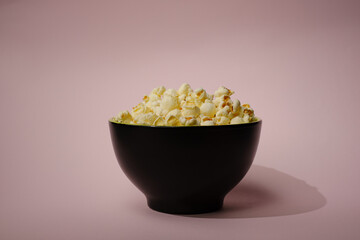 Popcorn looked down from above on a yellow background. The bowl of popcorn was lying flat. Top View.